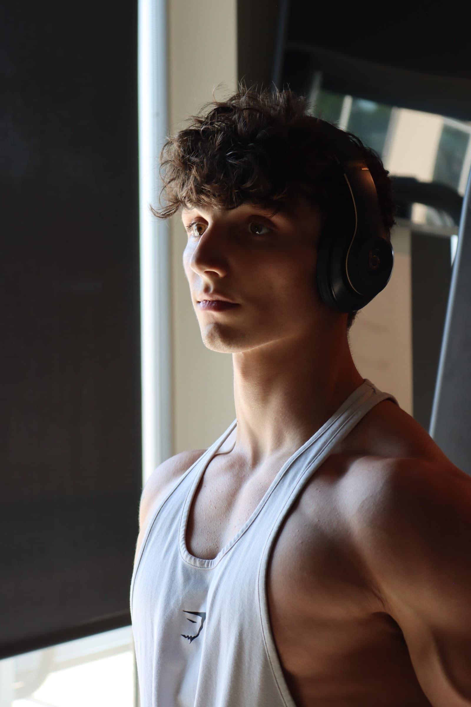 Kris Oddo, NASM-CPT, online fitness coach, mid-workout with headphones on in the gym